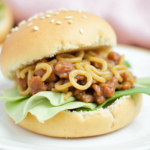 Sloppy joe sandwich with noodles, ground meat sauce, and lettuce in a sesame bun