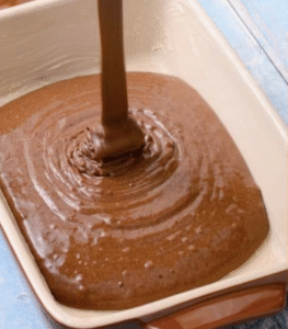 Chocolate cake batter poured into a round baking pan, ready to go into the oven for the Gâteau Délice recipe.