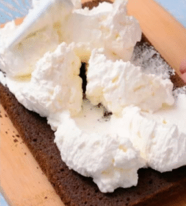 Spreading hazelnut mascarpone cream over the bottom layer of Gâteau Délice chocolate cake.