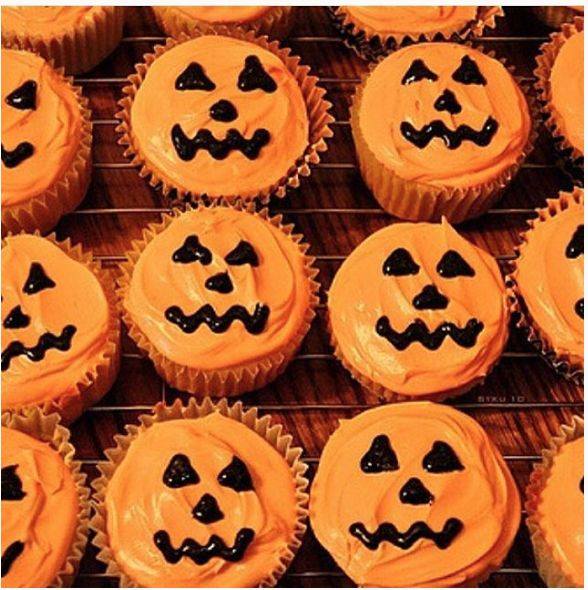 Halloween pumpkin cupcakes with orange frosting and black icing faces