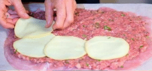 Stuffing the turkey roll with minced meat and cheese slices for the stuffed turkey roll recipe.