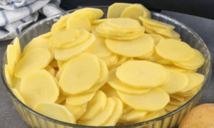 Preparing Potato and Bacon Pie ingredients — sliced potatoes, provola cheese, pancetta, and creamy béchamel sauce ready to layer.