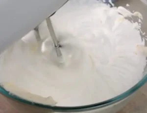 Mixing mascarpone cheese with sugar, honey, and orange zest in a bowl