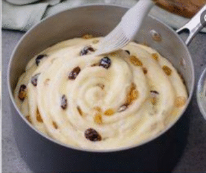 Brioche dough rolled into a spiral and placed inside a round baking pan before rising.