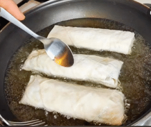 Frying golden phyllo rolls filled with tuna and potato mixture