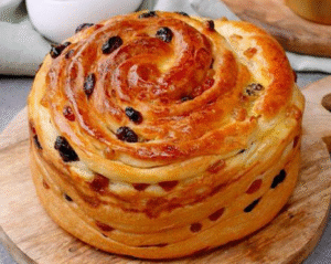 Freshly baked raisin brioche with a golden swirl and glossy surface.