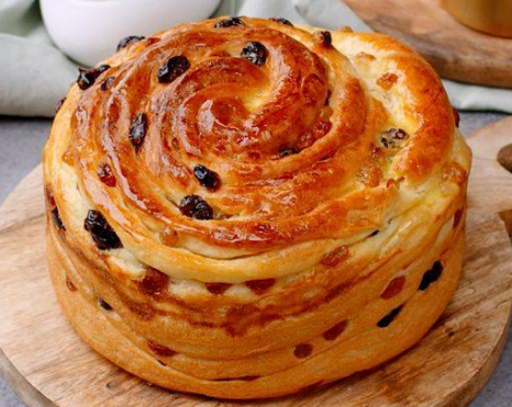 Freshly baked raisin brioche recipe with a golden swirl and glossy surface.