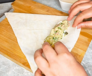Filling and rolling crispy phyllo pastry with tuna and potato mixture
