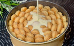 Pouring cream over ladyfingers to prepare the peach charlotte dessert