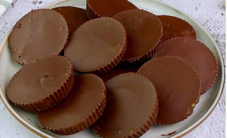A plate of homemade chocolate peanut butter cups with smooth chocolate tops.