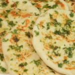 soft and fluffy naan bread recipe cooked in a pan, golden and slightly charred.