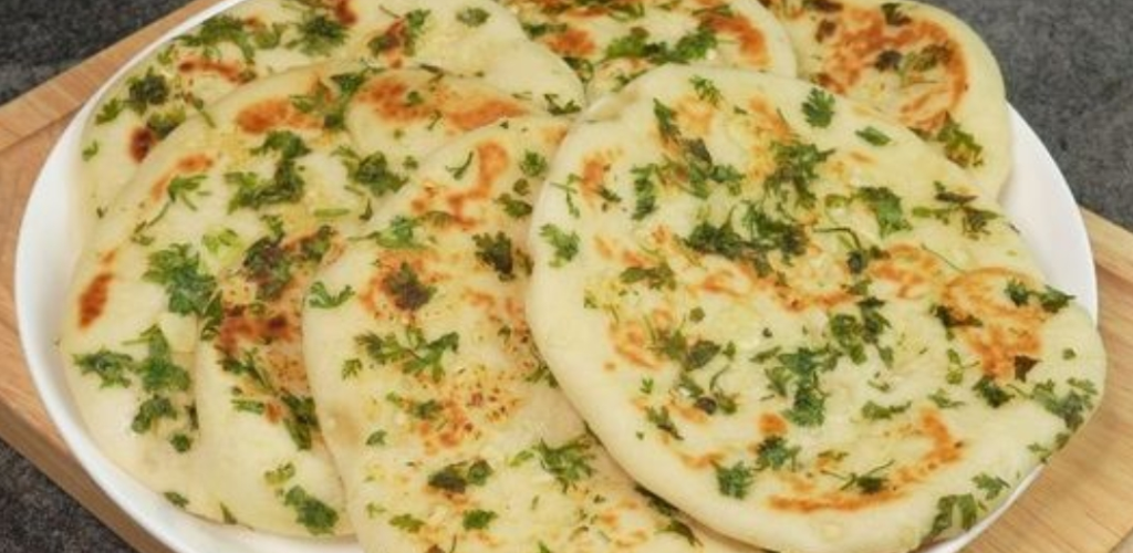 soft and fluffy naan bread recipe cooked in a pan, golden and slightly charred.