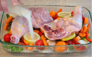 raw chicken legs with fresh vegetables in a baking dish