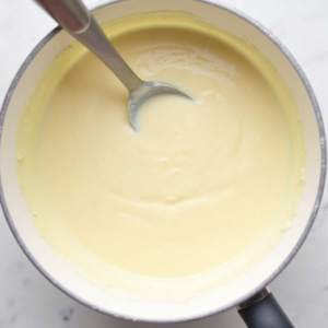 Cooking vanilla dessert cream mixture with milk eggs sugar and cornstarch in saucepan