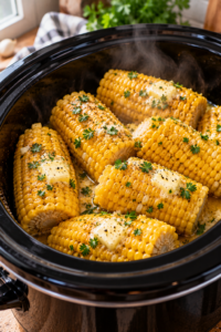 Finished slow cooker corn on the cob topped with melting butter, herbs, and black pepper.