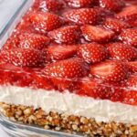 Strawberry pretzel salad in a glass dish with a crunchy pretzel crust, thick cream cheese layer, and glossy strawberry topping.