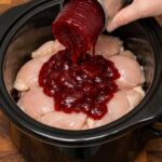 Amish Cranberry Chicken with cranberry sauce cooking in a slow cooker