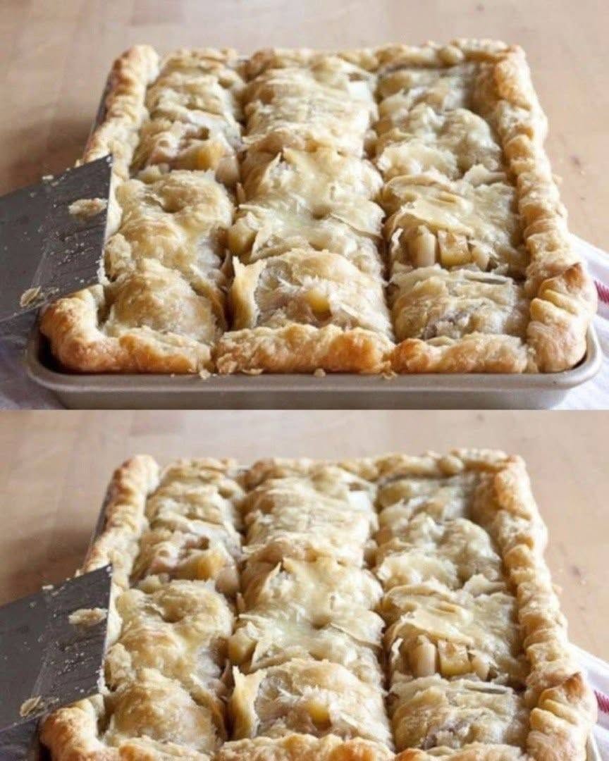 Apple slab pie cut into squares in a rectangular pan, with flaky pastry and visible apple filling.