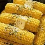 Slow cooker corn on the cob topped with melting butter, herbs, and black pepper.