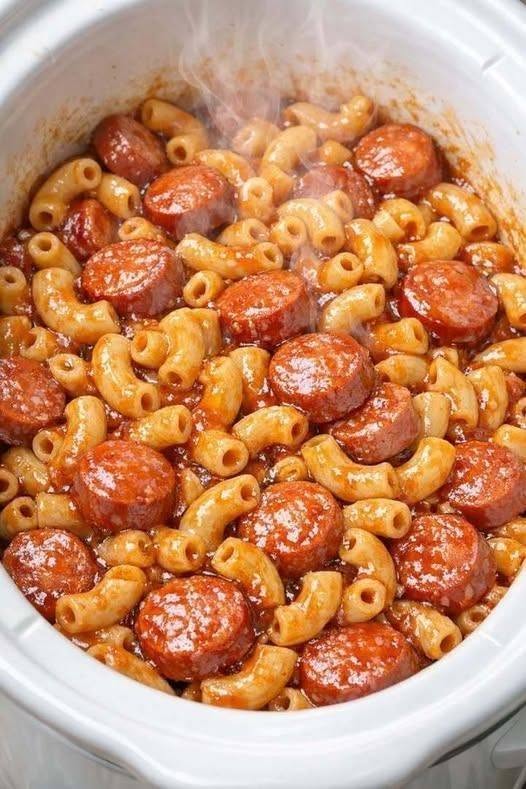 Slow cooker sausage pasta with elbow macaroni and sliced smoked sausage coated in tomato sauce.
