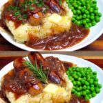Bangers and mash with browned sausages, mashed potatoes, onion gravy, and green peas.