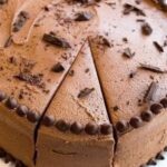 No-bake chocolate mousse cake with a dark cookie base, chocolate shavings, and one slice cut.