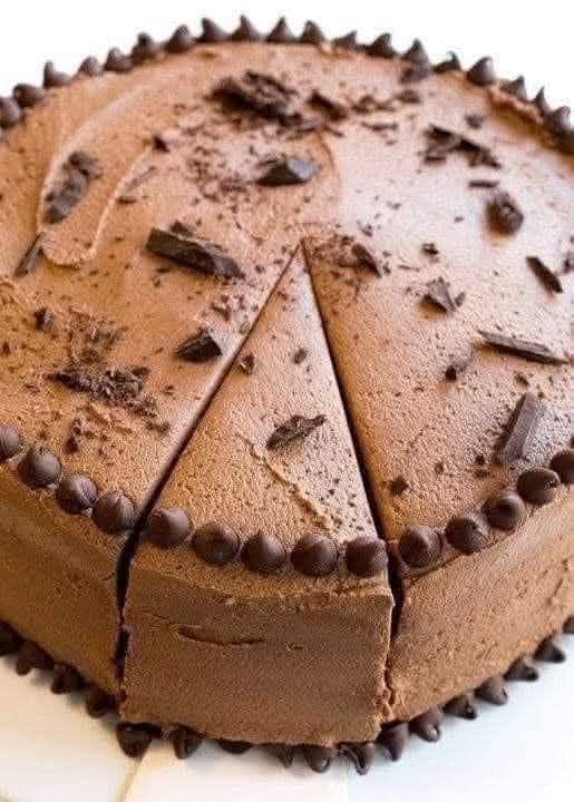 No-bake chocolate mousse cake with a dark cookie base, chocolate shavings, and one slice cut.