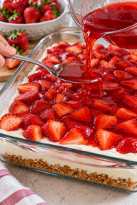 Strawberries and gelatin added over the cream layer of strawberry pretzel salad