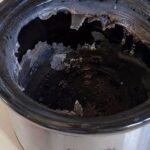 Cracked slow cooker insert with large broken areas and loose ceramic fragments