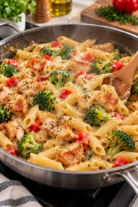 Chicken, broccoli, and pasta mixed with sauce for Creamy Chicken Broccoli Pasta Bake