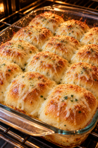 Cheesy garlic dinner rolls baking in a glass dish with mozzarella melting on top
