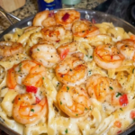 Creamy garlic shrimp pasta with fettuccine, Parmesan sauce, red bell pepper, parsley, and black pepper.