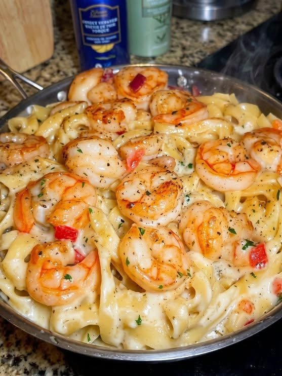 Creamy garlic shrimp pasta with fettuccine, Parmesan sauce, red bell pepper, parsley, and black pepper.