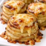 Oven-baked cheesy potato stacks on a white plate
