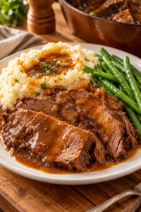 Slow cooker pot roast served with mashed potatoes, green beans, and gravy